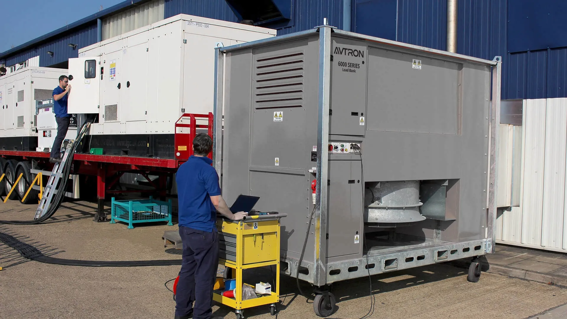 Technician running an Avtron load bank test beside a diesel standby generator