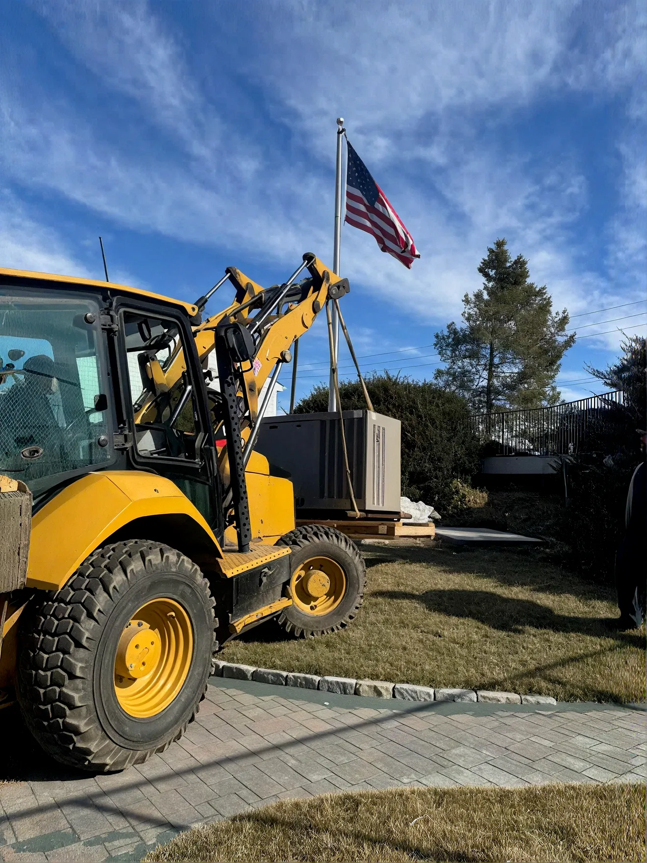 Backhoe positioning a generator at an install site